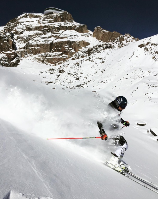 Powering down a steep slope beneath rocky peaks